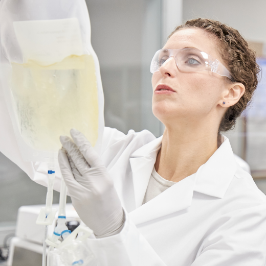 Scientist outfitted in PPE hangs a cell bag during cell therapy manufacturing