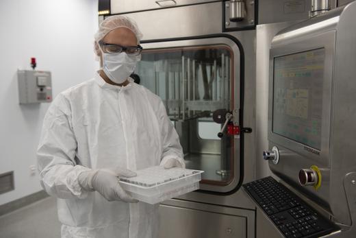 Cleanroom operator holds a tray of nested vials that have been filled and closed by the SA25 Aseptic Filling Workcell.