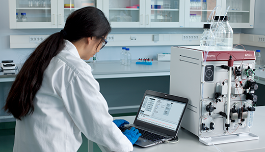 Scientist and ÄKTA go protein purification system preforming column chromatography
