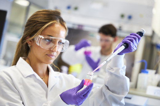 Close up of scientist using a pipette at lab bench, mask off, looking down, close up, side view 2 (high res)