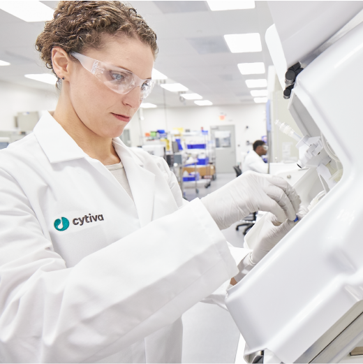 Scientist outfitted in PPE places a cell bag into the Xuri cell expansion system